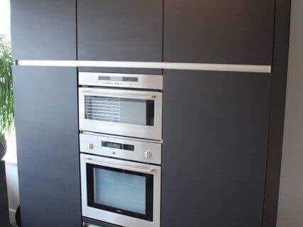 Resultaat van het laten wrappen van een saai wit keukenblok naar een moderne donkere look